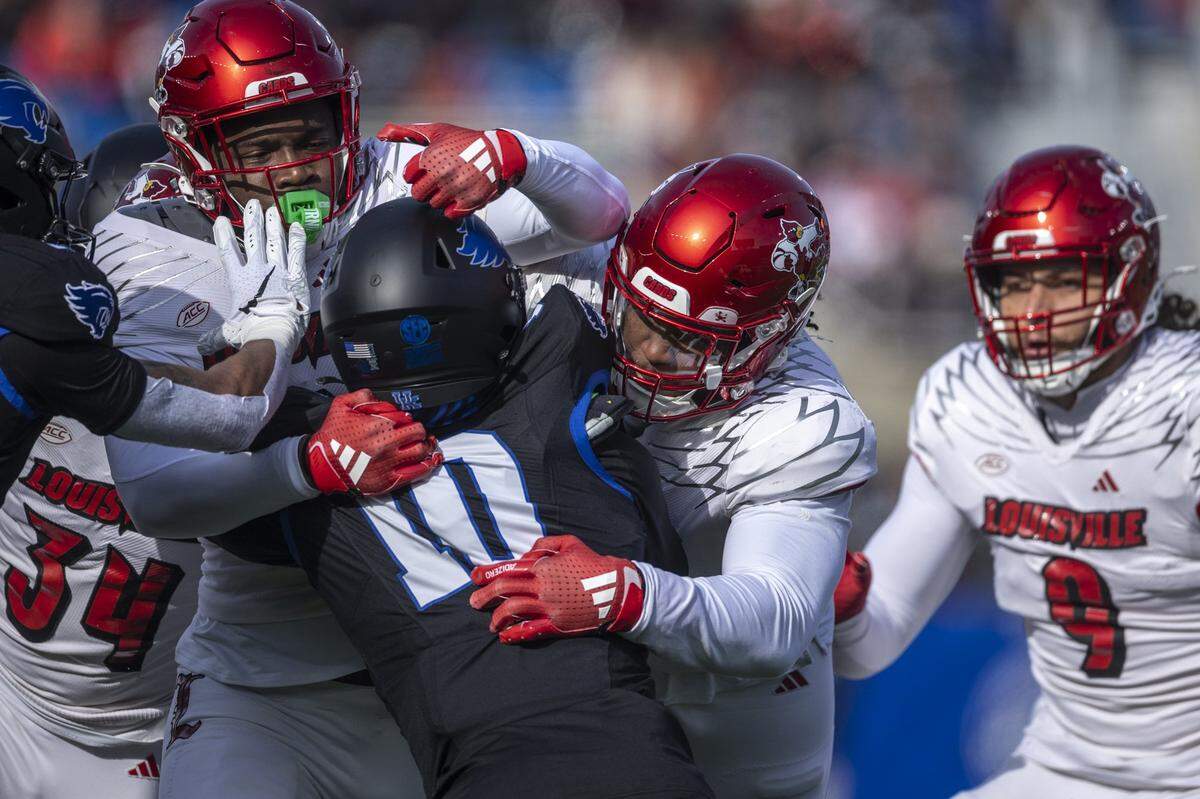 Kentucky running back Jamarion Wilcox (10) is wrapped up by a wall of Louisville defenders during Saturday’s game at Kroger Field.