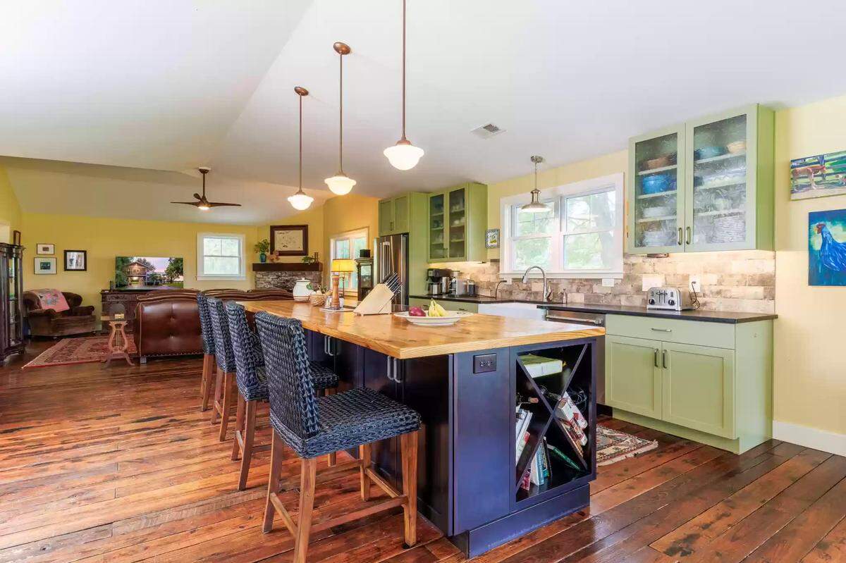 A view of the kitchen at 4351 Bethel Road. The kitchen has an island that is painted a deep blue. Both the kitchen and the living share a large, open-concept space. 