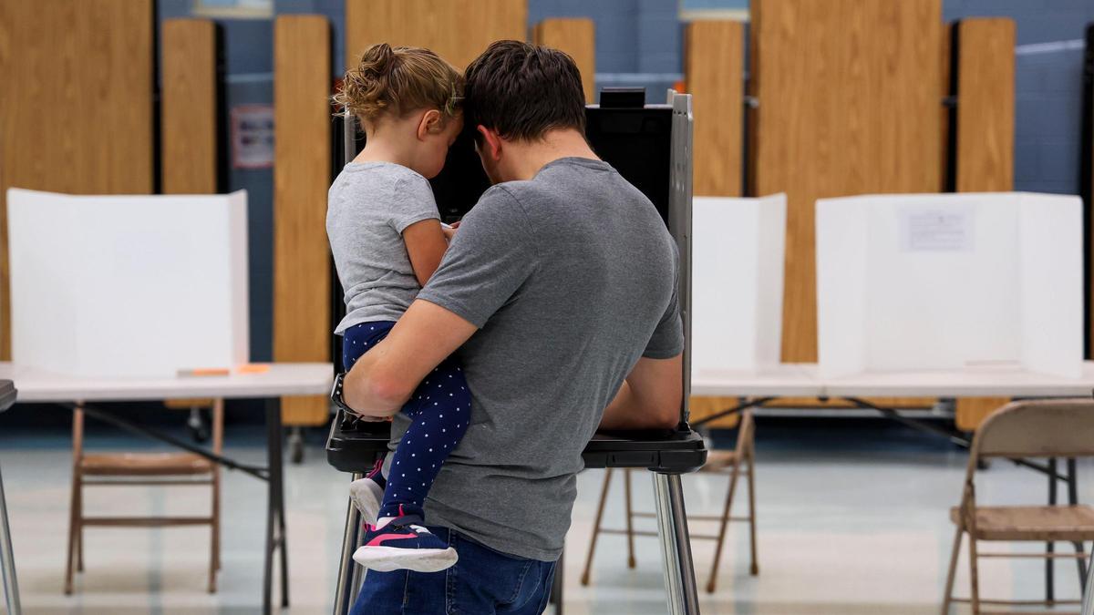 A voter cast his ballot in the 2024 general election as he holds a little girl at Lansdowne Elementary School, Tuesday, Nov. 5, 2024 in Lexington, Ky.