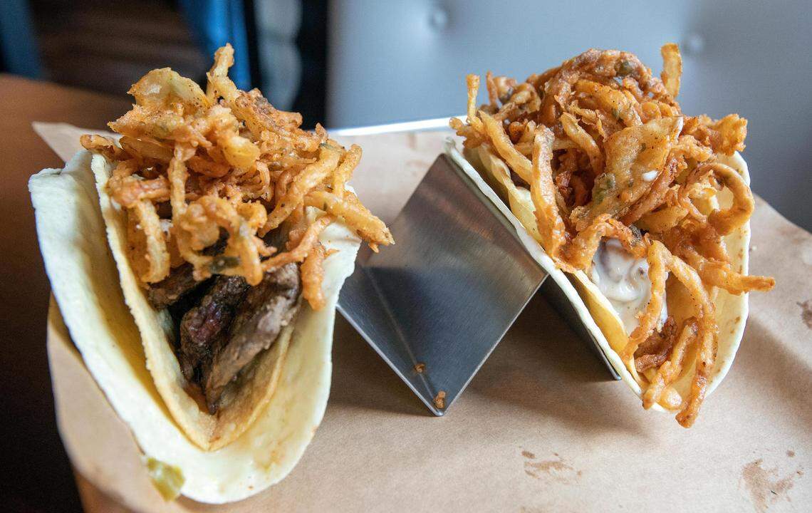 The Bomb taco at Agave & Rye, left, features carne asada steak, chopped bourbon-poached shrimp, mac ‘n cheese A&R spicy chili & BBQ jam and tobacco onions. The Bama Jamma, right, has Alabama white BBQ chicken, andouille sausage, roasted corn and tobacco onions.