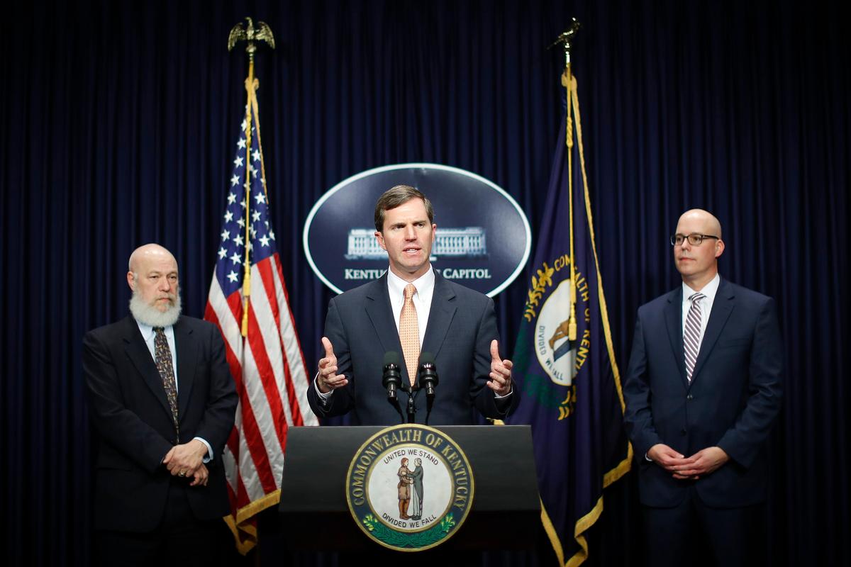 Acting Secretary of the Kentucky Cabinet for Health and Family Services Eric Friedlander, left, and Kentucky Department for Public Health Commissioner Dr. Steven Stack, right, listen as Kentucky Gov. Andy Beshear speaks during a news conference on COVID-19 or coronavirus at the state Capitol in Frankfort, Ky., Thursday March 5, 2020.