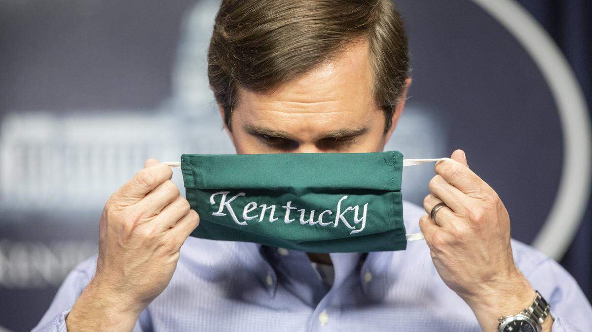 Kentucky Gov. Andy Beshear puts on a face mask after speaking at a media conference at the state Capitol in Frankfort, Ky., to provide an update on the novel coronavirus Monday, May 11, 2020.