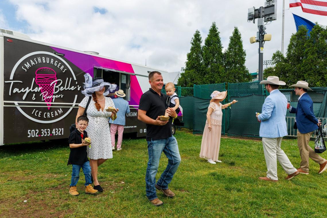 Mike Carroll, carrying Ava, right, with wife Ashley and Shaun, get burgers from Taylor Belle’s & Burgers truck in the infield on Derby Day, Saturday, May 4, 2024 at Churchill Downs in Louisville, Ky.
