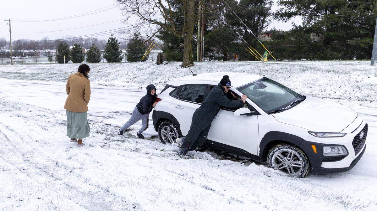 Kyle Dick and his son, Jesse help a stranded motorist by pushing their car back onto Old Todds Road, Tuesday, March 17, 2026 in Lexington, Ky. Slippery road conditions caused many crashes across the city after winter weather moved through the area.