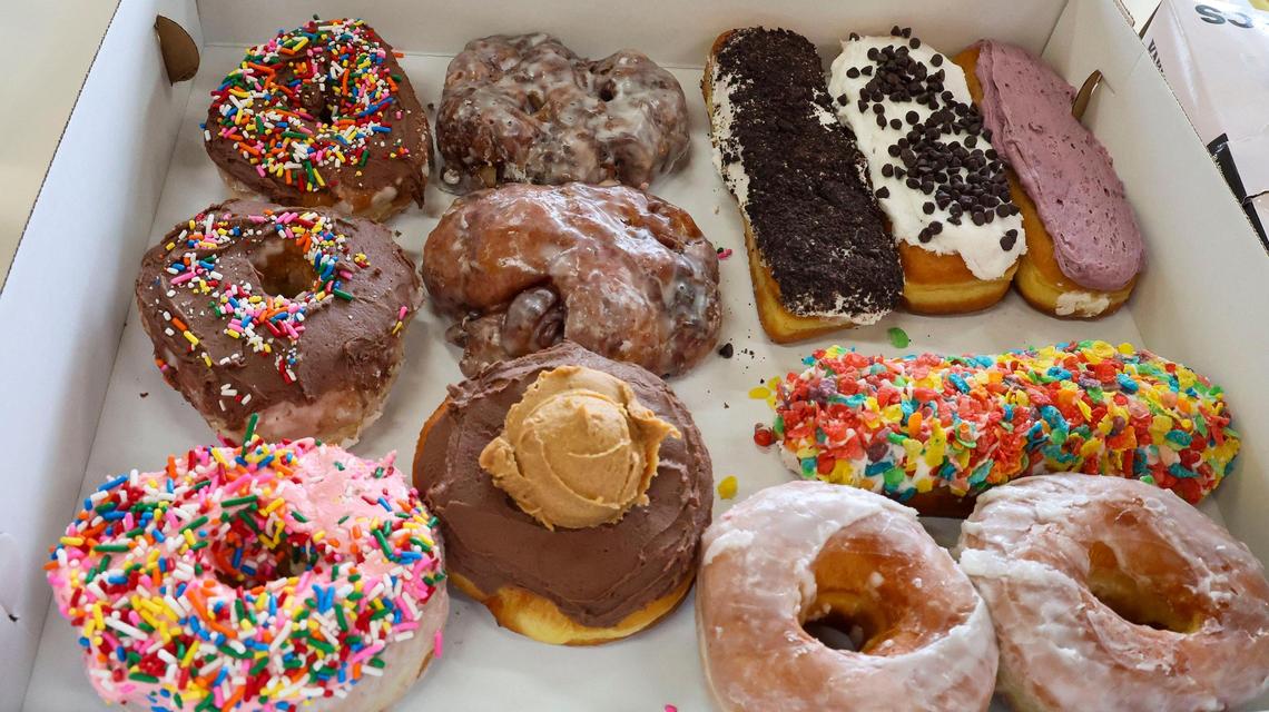 A variety of a dozen doughnuts from Jeff’s Donuts, Thursday, Jan. 23, 2025, in Lexington, Ky. The new-to-Lexington doughnut shop is opening a location near downtown and the University of Kentucky campus on South Broadway. Doughnuts shown include clockwise from top, chocolate iced sprinkles, apple fritters, vanilla iced cookies and cream long john, vanilla iced chocolate chips long john, blueberry iced cream filled long john, vanilla iced fruity pebbles long john, original glazed, chocolate peanut butter honeymooner and strawberry iced sprinkles.