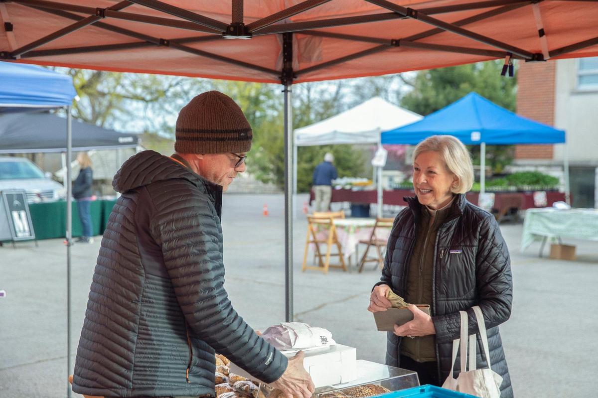 Sue Wilmes of Lexington buys baked goods from Andy Brown – including a loaf of rye bread, made with Kentucky-grown rye – at the Chevy Chase Farmers Market at Apostles Anglican Church in Lexington, Ky., on Wednesday, April 20, 2022.