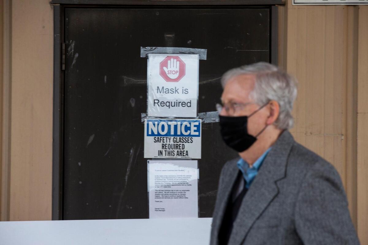 A sign stating that masks are required appears on a door behind Senate Majority Leader Mitch McConnell while he listens to Congressman Andy Barr speak at a campaign event in front of Custom Tool and Manufacturing in Lawrenceburg, Ky., Wednesday, October 28, 2020.