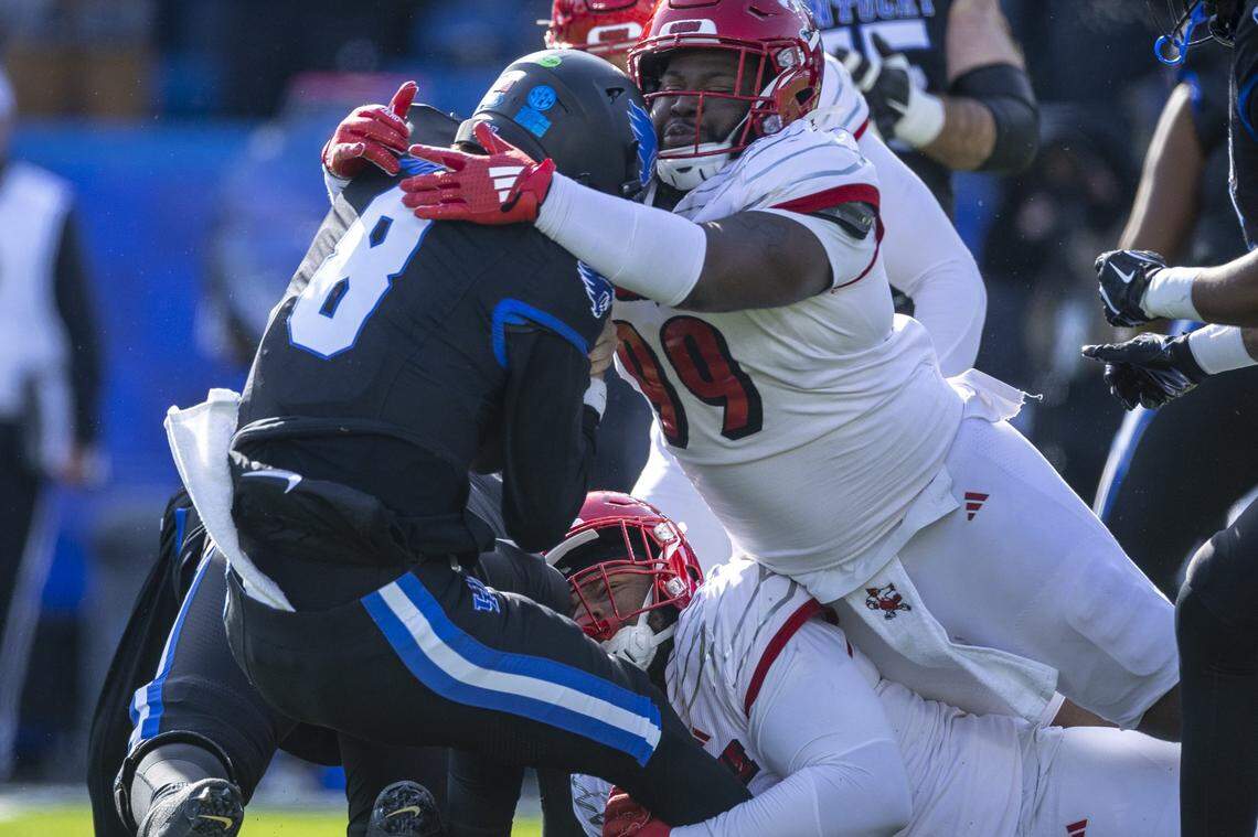 Kentucky quarterback Cutter Boley (8) is sacked by Louisville defensive linemen Rene Konga (90) and Dezmond Tell (99) during Saturday’s game at Kroger Field.