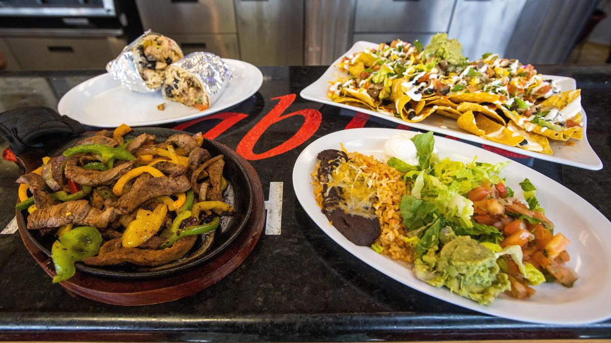 Clockwise from the top, a burrito, super nachos, mango salsa with beans and rice and steak fajitas.