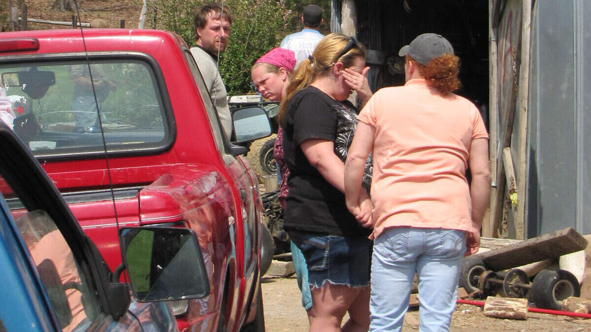 A friend comforted Elizabeth Osborn, center, on Wednesday outside the mobile home in rural Metcalfe County where the parents of Osborn's boyfriend were slain the day before.   