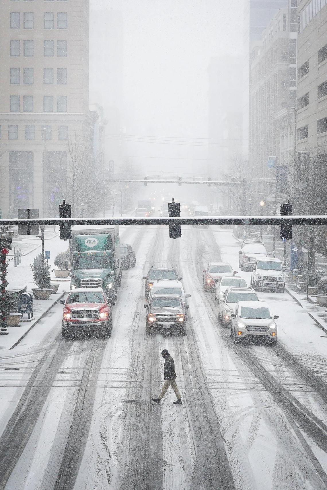 A man crosses a snow covered West Main Street on Mill street as snow continues to accumulate through Lexington, Ky., Thursday, Jan. 6, 2022.