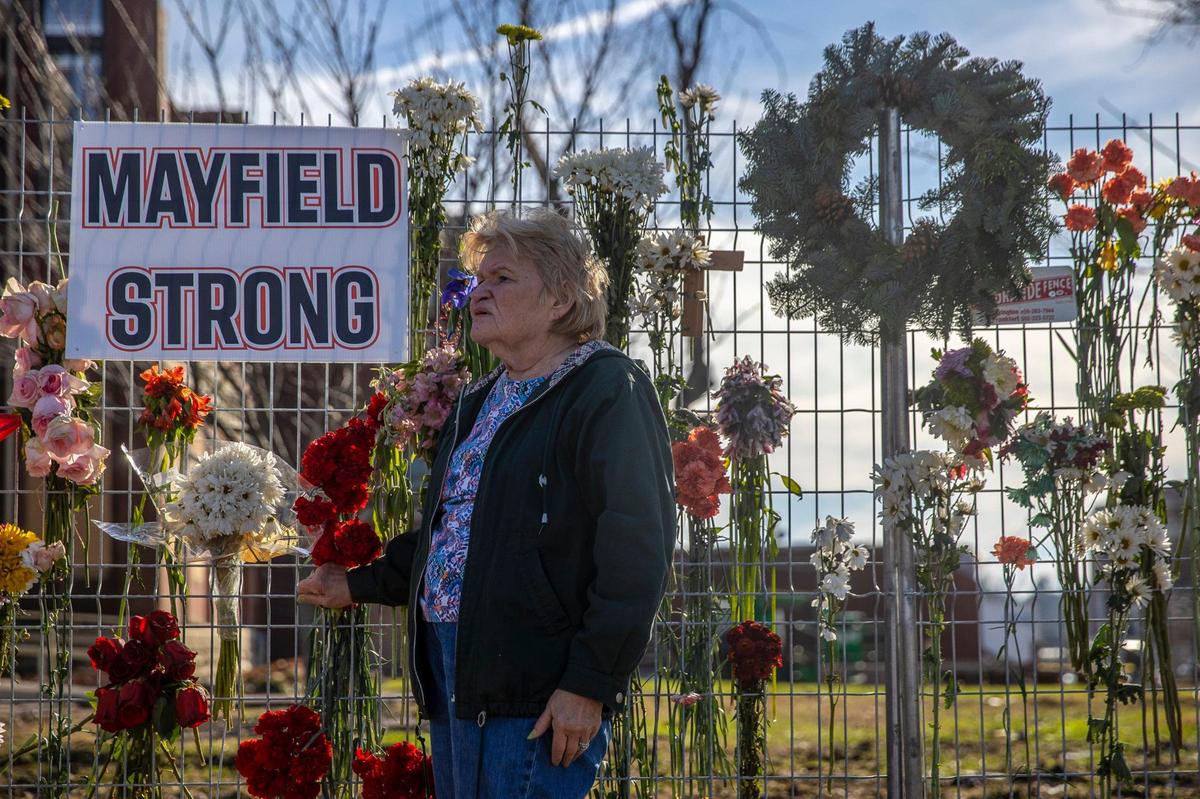 Nancy Rambo stands near a memorial for victims of the tornadoes that struck Kentucky earlier this month on a temporary fence outside the Graves County Courthouse in Mayfield, Ky., on Monday, Dec. 20, 2021.