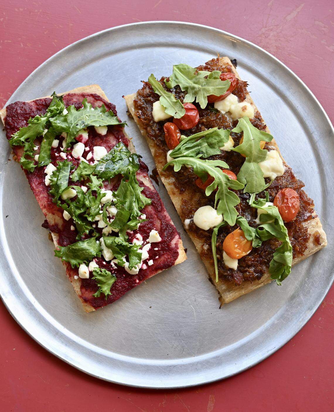 At left from Dingbats, the Ginsberg with pink beet pesto, goat cheese, endive, mimosa vinaigrette. And at right, the Buford with bacon jam, heirloom cherry tomatoes, arugula, fontina. 