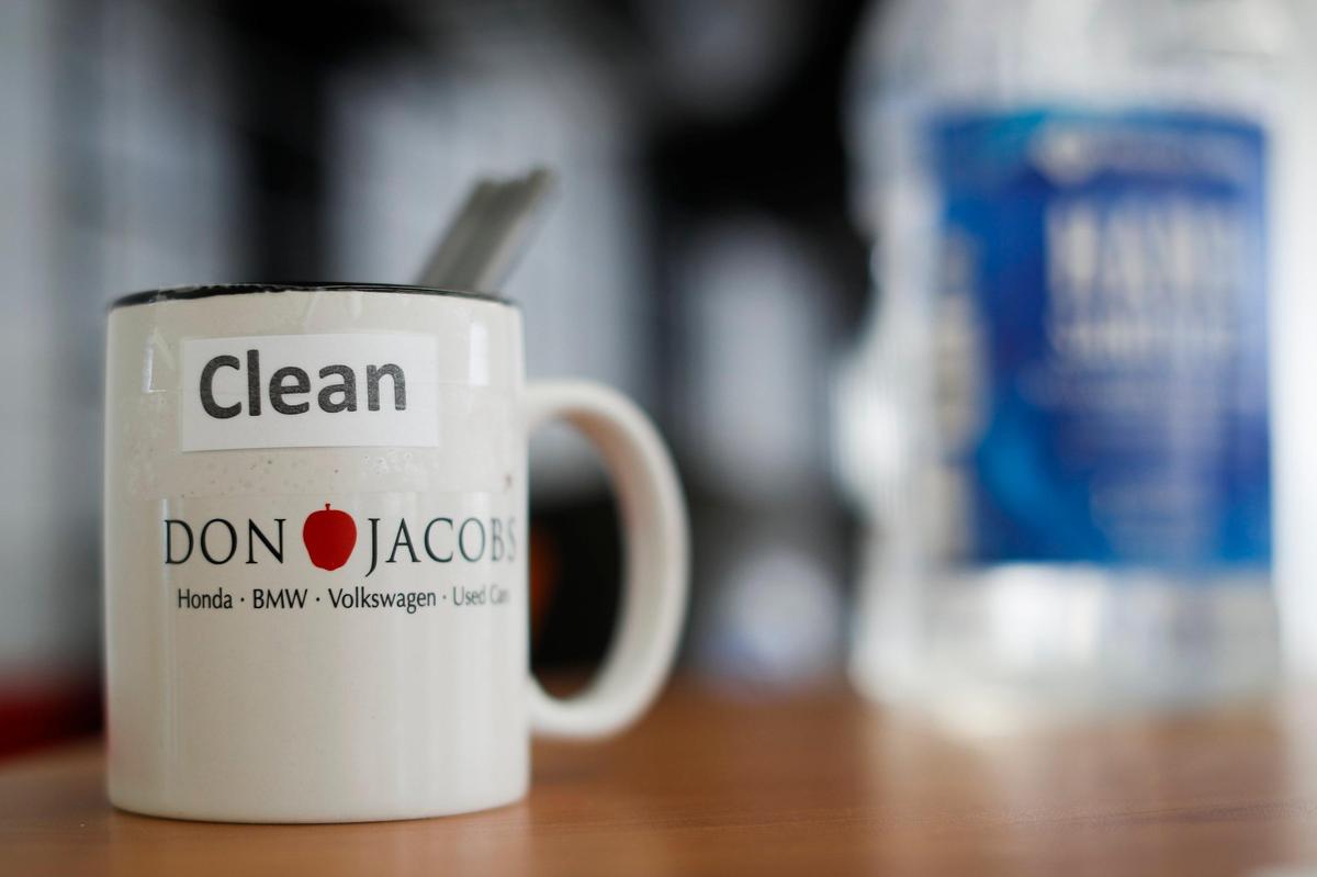A mug of clean pens sits next to a bottle of hand sanitizer Friday at Don Jacobs dealerships off Nicholasville Road.
