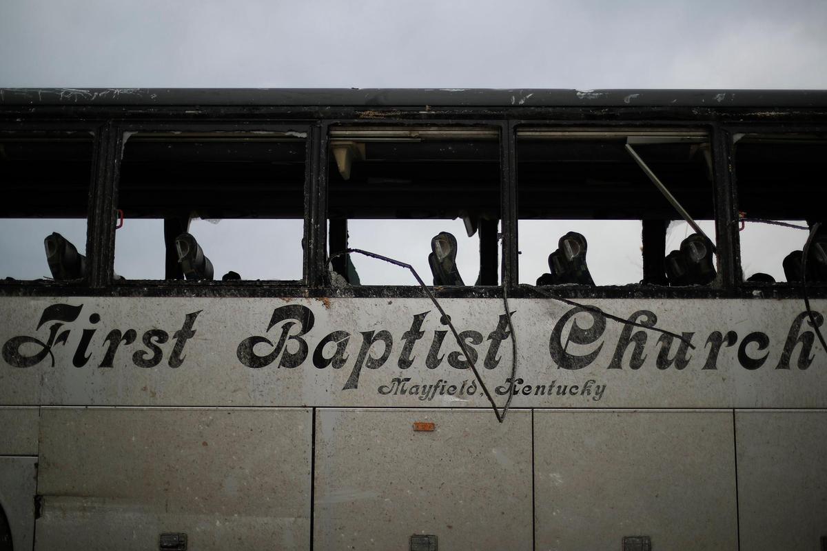 A bus belonging to First Baptist Church sits with blown out windows and a destroyed interior near the Mayfield church.