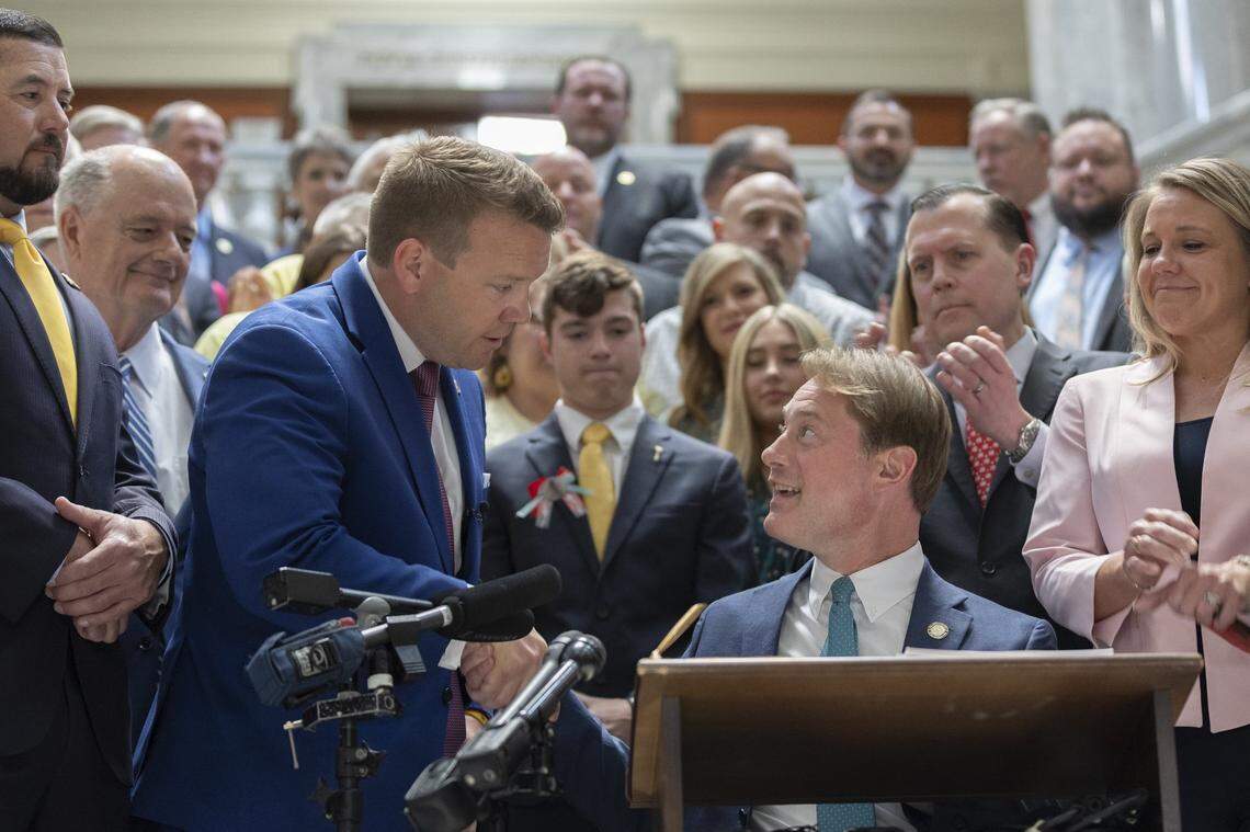 Kentucky state Rep. Jared Bauman, R-Louisville, standing, shakes hands with Kentucky Secretary of State Michael Adams before Adams signed House Bill 5, the Safer Kentucky Act, at the Kentucky state Capitol in Frankfort, Ky., on Monday, April 15, 2024. The bill, sponsored by Bauman, was vetoed by Gov. Andy Beshear before the legislature overturned the veto.