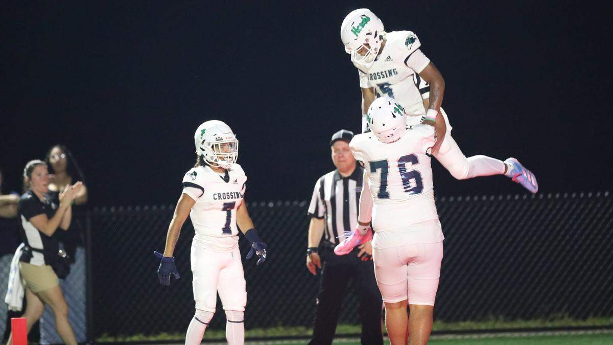 Great Crossing’s Wyatt Seekford (76) lifts his teammate, Jeremiah Clark (5) after his touch down during Scott County’s first home game in 30 years at Cardinals Stadium on August 30, 2024, in Lexington, Ky