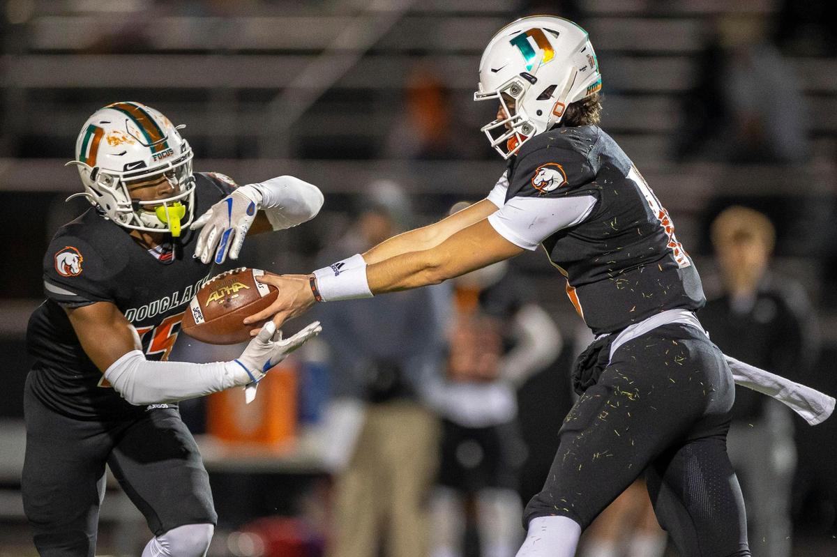 Frederick Douglass’ Samuel Cornett (10) hands off the ball to TJ Horton (15) during a Class 5A semifinal game against Owensboro at Frederick Douglass High School in Lexington, Ky., on Friday, Nov. 26, 2021.