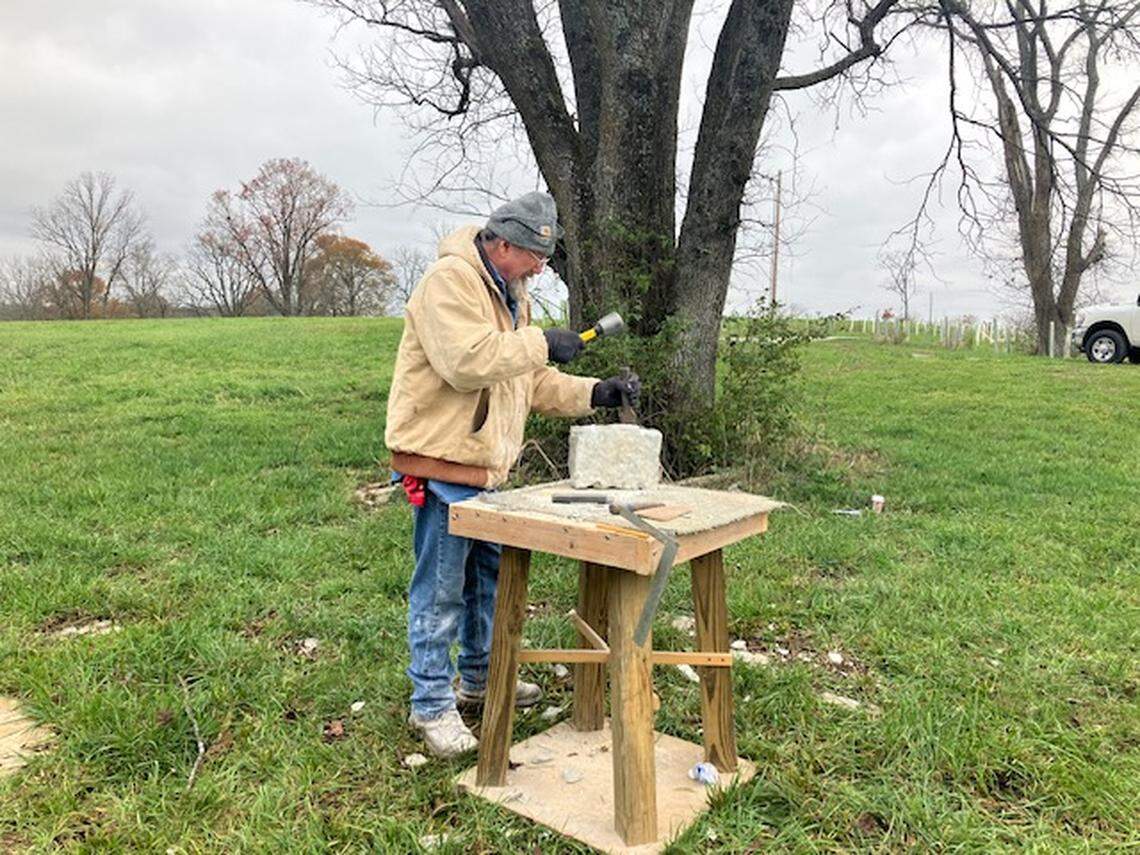 Don Hopper of Berryville, Ark., uses a hammer and chisel to shape limestone rock at a Dry Stone Conservancy workshop in Jessamine County on Nov. 22, 2024.