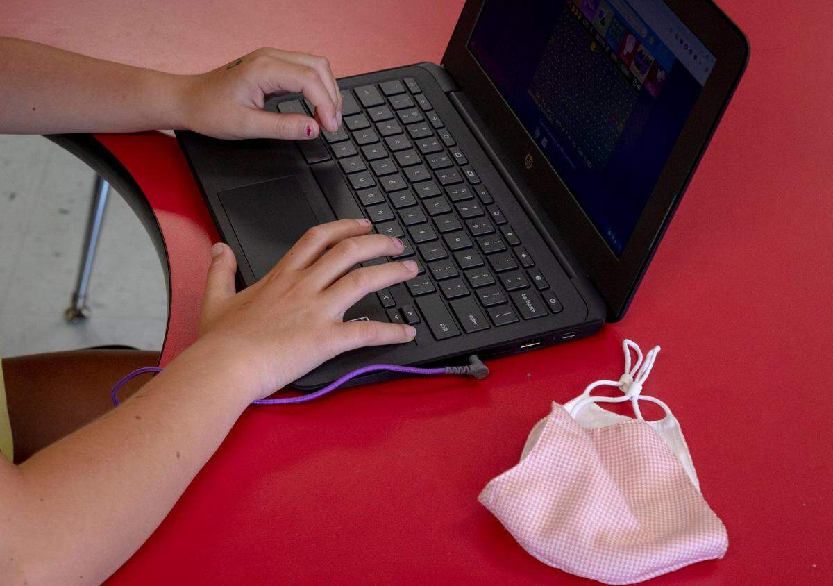 A mask lays next to a school Chromebook.