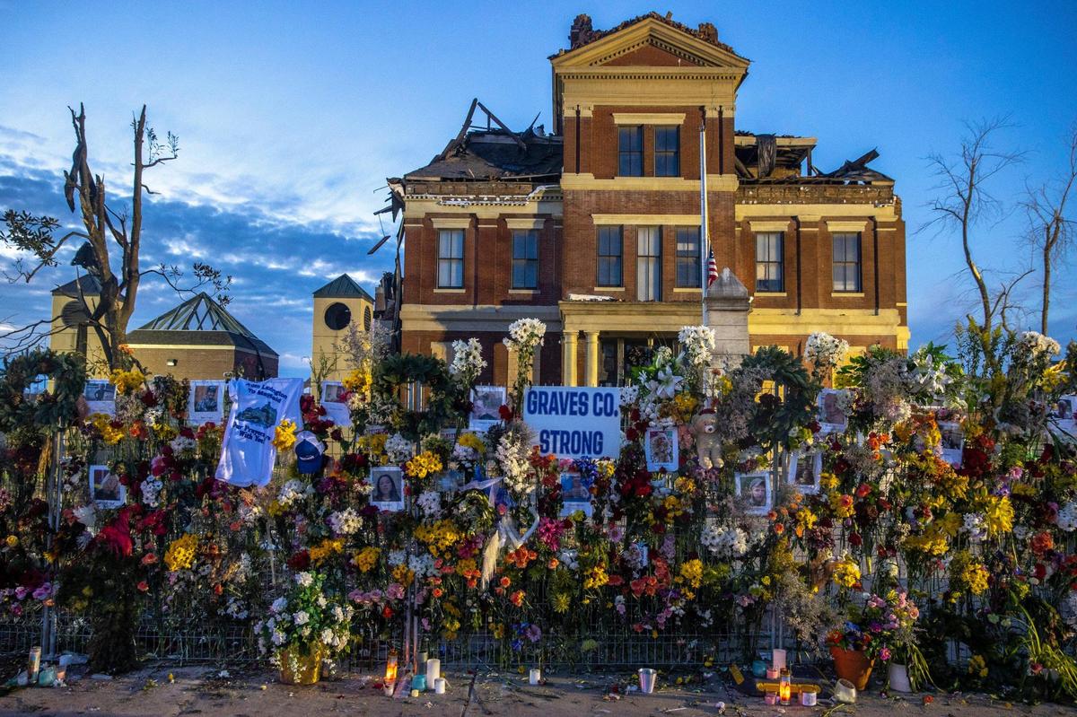 Flowers are placed on a temporary fence outside the Graves County Courthouse in Mayfield, Ky., on Monday, Dec. 20, 2021.
