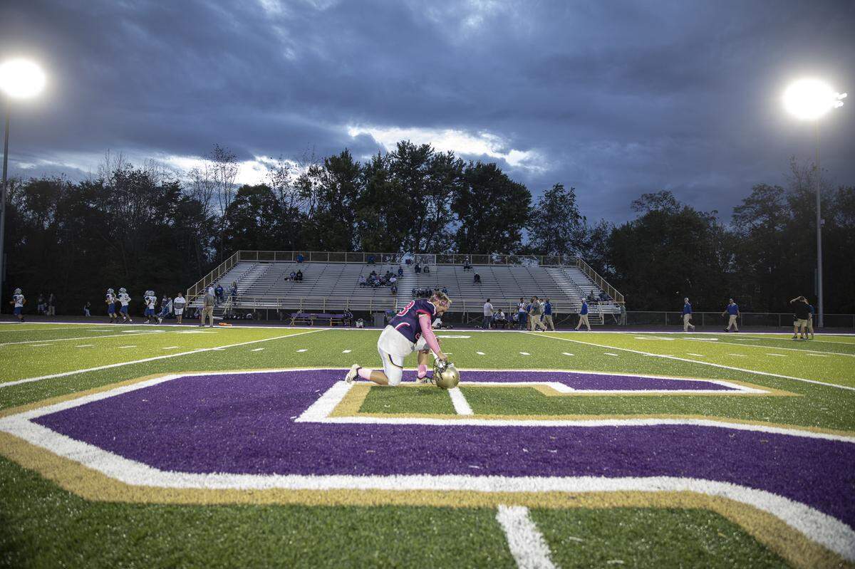 Somerset’s Andrew Childers takes a knee and bows his head at the 50-yard line before the start of the game.