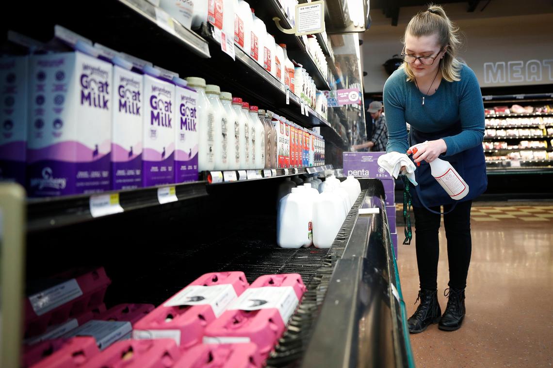 Tiffany McGowan works to disinfect the dairy case Wednesday at Good Foods Co-op.