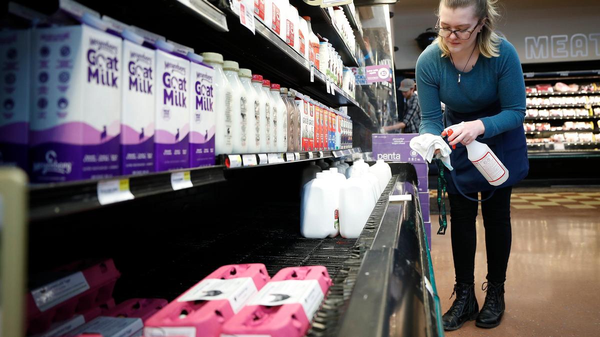 Tiffany McGowan, of Versailles, Ky., works to disinfect the dairy case at Good Foods Co-op in Lexington, Ky., in 2020. Grocery prices are increasing, the U.S. Bureau of Labor Statistics reported Thursday.