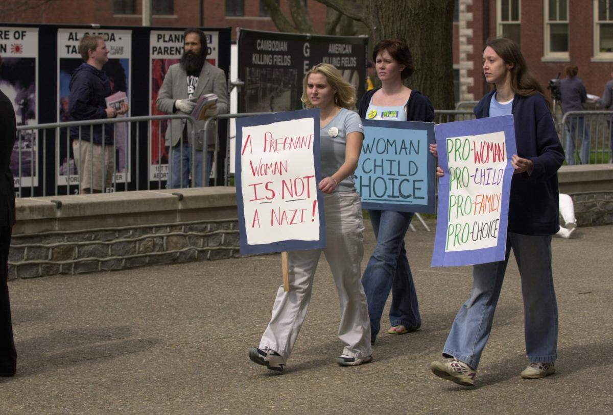 Pro-choice activists protest the anti-abortion display with their own signs as they walk past people handing out anti-abortion literature and graphic photos of aborted fetuses on display by the Center for Bio-Ethical Reform on the University of Kentucky Campus in Lexington, Ky., on April 8, 2002. From left is UK student Krista Elliott, Transy student Kristin Todd, and UK student Joy Carr. The CBR’s Genocide Awareness Project is a display of murals comparing abortion to other forms of historical genocide including the holocaust, and slavery in the United States.