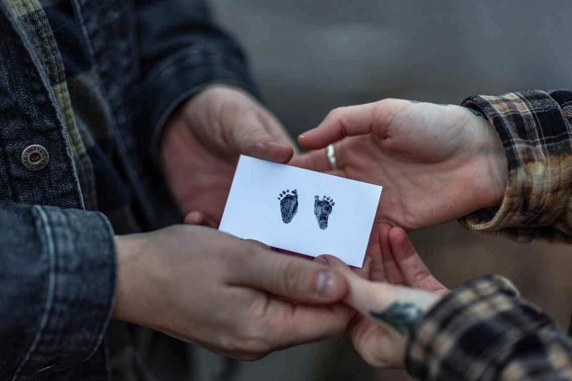 Stephen Montgomery and Genevieve Postlethwaite hold a card with the footprints of their child in Murray, Ky., on Wednesday, Dec. 25, 2025. in July, Postlethwaite had a severe complication in her pregnancy that made it nonviable. But because of Kentucky’s abortion laws, they had to hastily go to Illinois to get an abortion