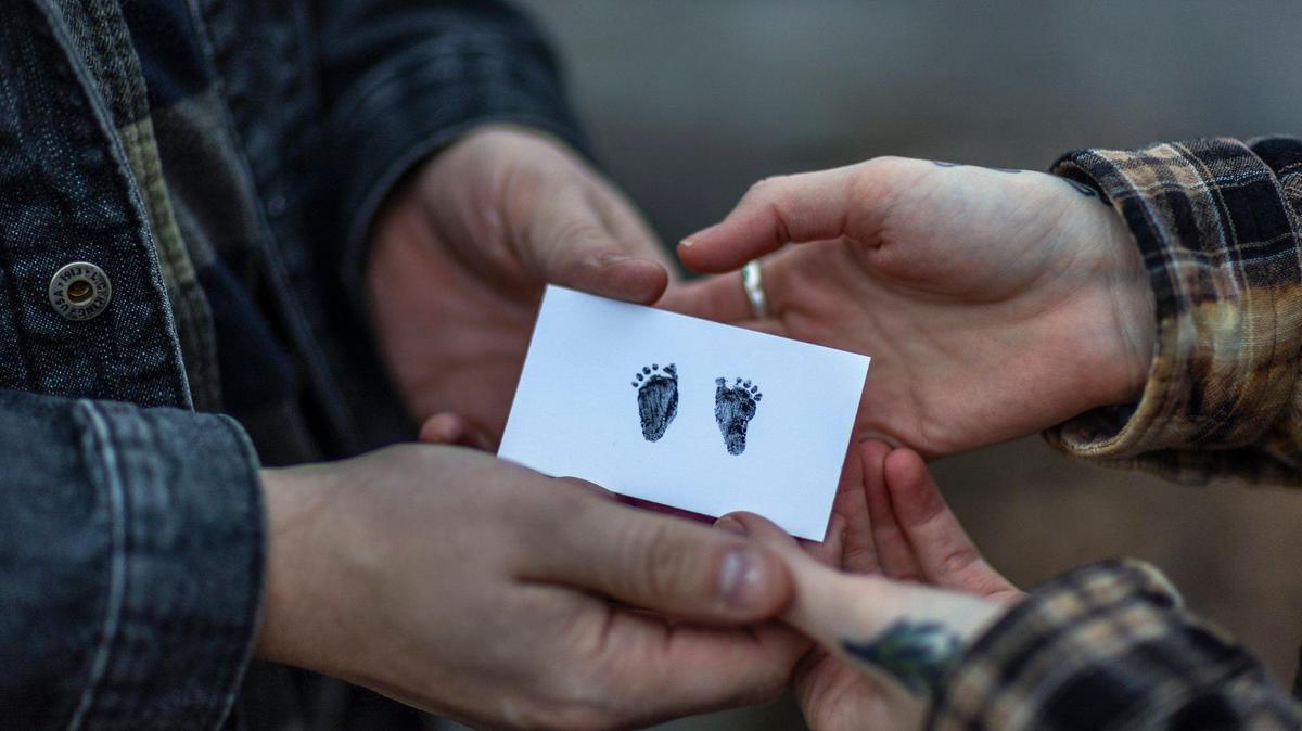 Stephen Montgomery and Genevieve Postlethwait hold a card with the footprints of their child in Murray, Ky., on Wednesday, Dec. 25, 2025. in July, Postlethwaite had a severe complication in her pregnancy that made it nonviable. But because of Kentucky’s abortion laws, they had to hastily go to Illinois to get an abortion.