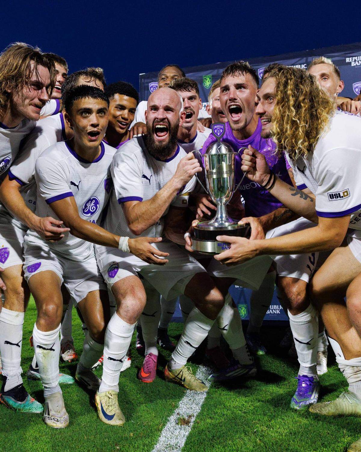 Members of the Louisville City soccer team celebrate with the Commonwealth Cup trophy following a 2-1 win over Lexington Sporting Club on Saturday at Lexington SC Stadium.