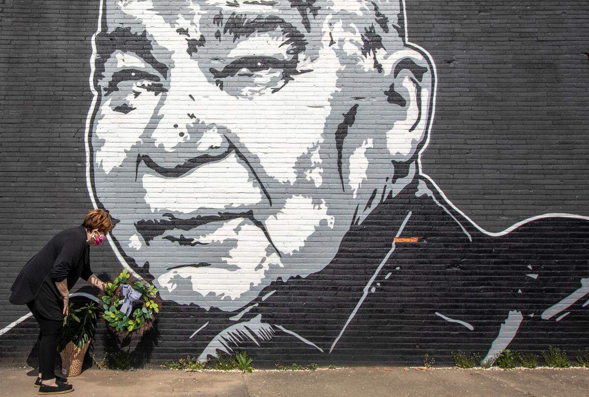Maribeth Schmitt, of Lexington, Ky., placed a wreath below a mural of singer John Prine, on the side of Apollo’s Pizza in Lexington, Ky., on Wednesday, April 8, 2020. Prine, 73, died April 7.