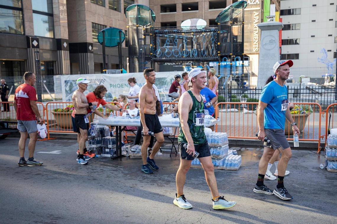 Runners grab drinks to rehydrate after crossing the finish line.