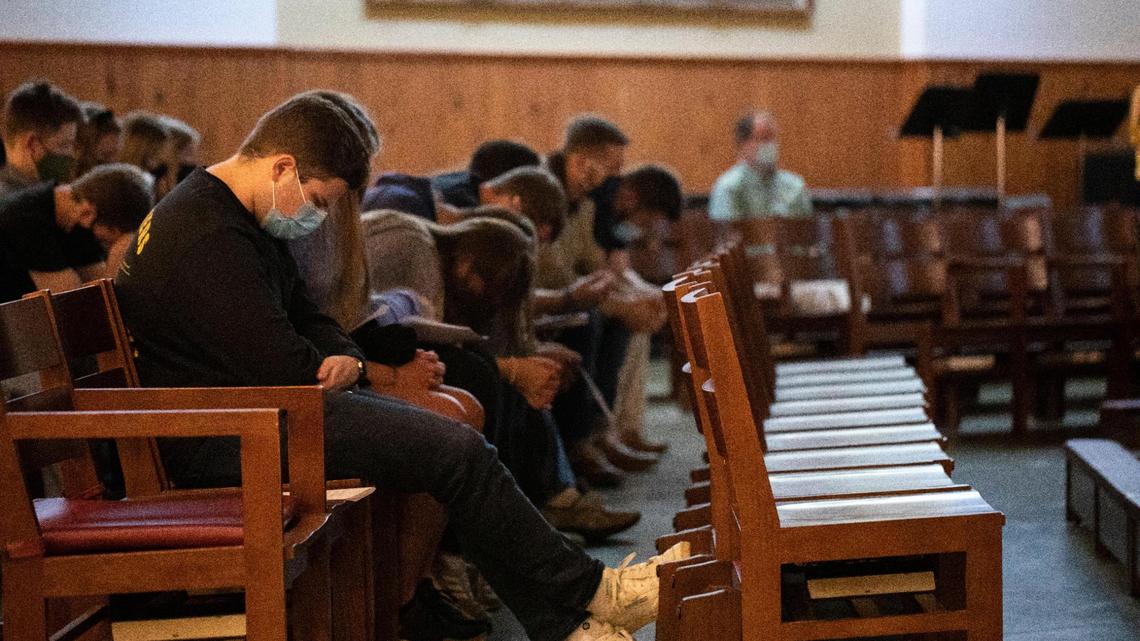 People bow their heads while gathering at the Holy Spirit Parish Catholic Newman Center for a campus prayer vigil and mass for Thomas Lofton Hazelwood, who died Monday night after being found at the frat house in Lexington, Ky., Thursday, October 21, 2021.