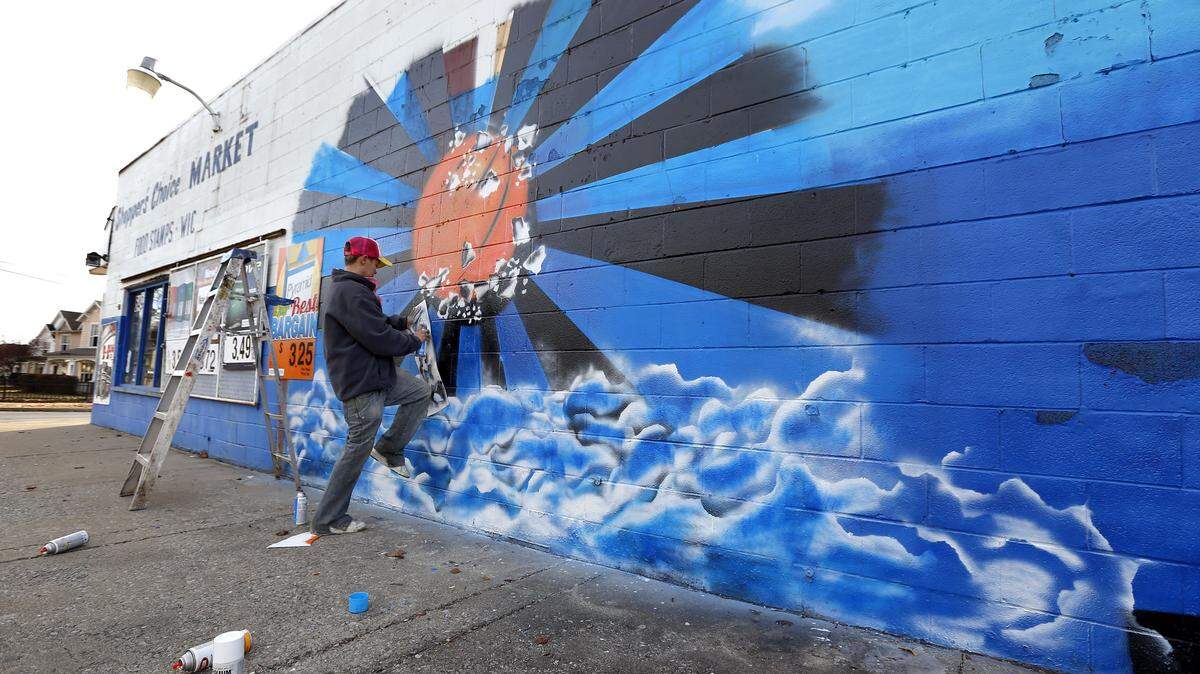 Artist Dani Greene painted a mural on the side of the Shopper's Choice Market at 649 Georgetown St. in Lexington on Thursday. With the money from this project she plans on buying paint to do a mural at the Marathon on Alexandria Drive where her friend Mukeshbhai Patel was killed Dec. 9.  