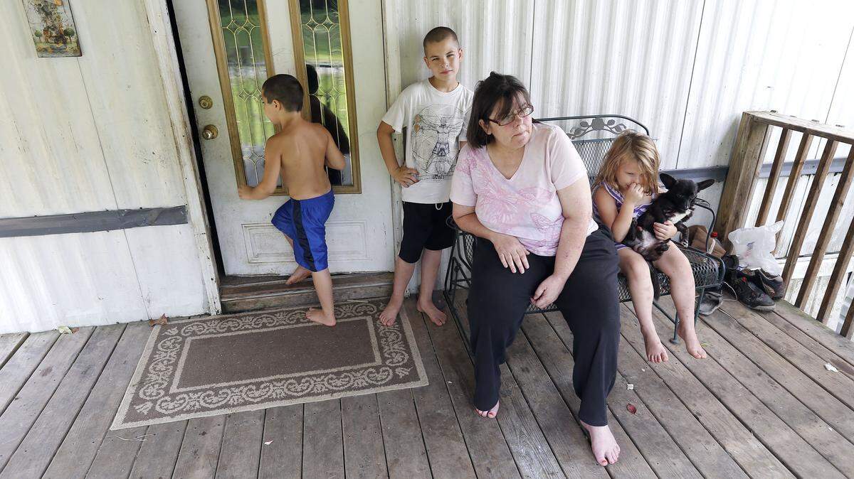 Kathy Howell of Inez and her family — her husband, a grown daughter and six grandchildren — get by on disability ­payments and food stamps. With her in August were grandkids Caleb ­Savage, 7, left; Corey Savage, 10, and Gabby Marcum, 6. Photo by Charles Bertram | Staff
