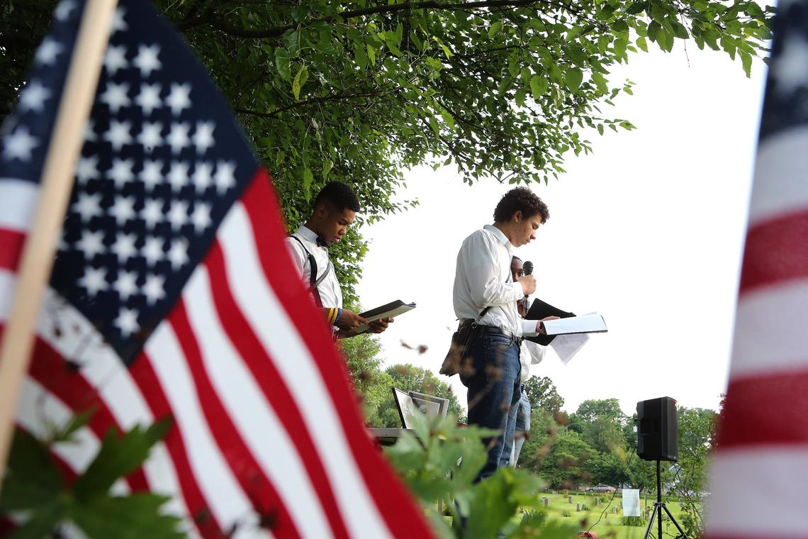 TeSean Owens, left, Nino Owens and Joshua Bredwood, not seen, read the roll call of Civil War veterans buried on site Saturday evening during the Juneteenth Jubilee at African Cemetery No. 2 on Seventh St. in Lexington. Photo by Matt Goins