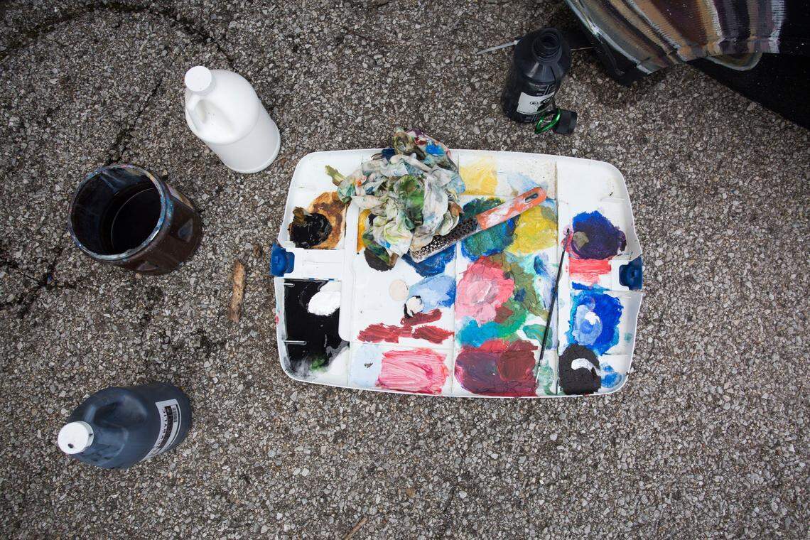 Paint and art supplies sit near by Stevie Moore as he touches up his bench at the old bus depot in Lexington on Tuesday. 