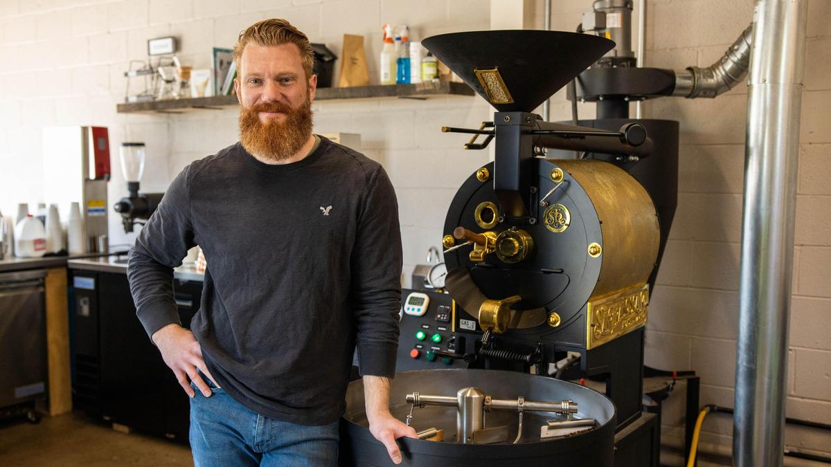 David Barnes, owner of Jefferson Street Coffee, stands next to a San Franciscan coffee roaster which is used to roast 10 pounds of coffee to bag and sell as Smokin’ Aces coffee.
