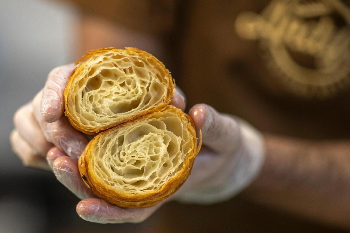 Andy Bissell holds up a croissant cut in half at Andy’s Artisan Bread at 127 E. Todd St. in Frankfort, Ky., on Thursday, July 21, 2022.