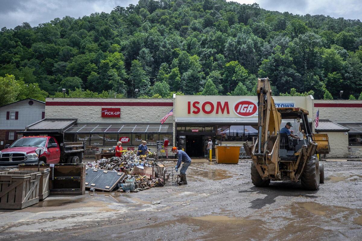 Workers pile canned foods and other grocery items from Isom IGA outside the store on Monday, Aug. 1, 2022. All of the food had to be thrown out after the store was flooded.