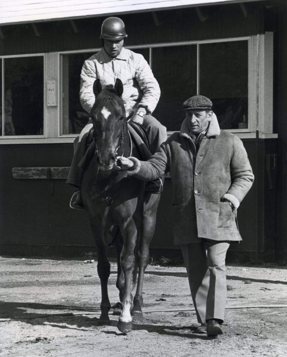 US Racing Hall of Fame trainer Ángel Penna Sr. leading Flying Water, with exercise rider Jean Pierre up, at Belmont Park in Elmont, New York. The photo is undated, but Penna Sr. conditioned hundreds of graded stakes race winners during a career that began in 1950 and lasted for more than 40 years on three continents.