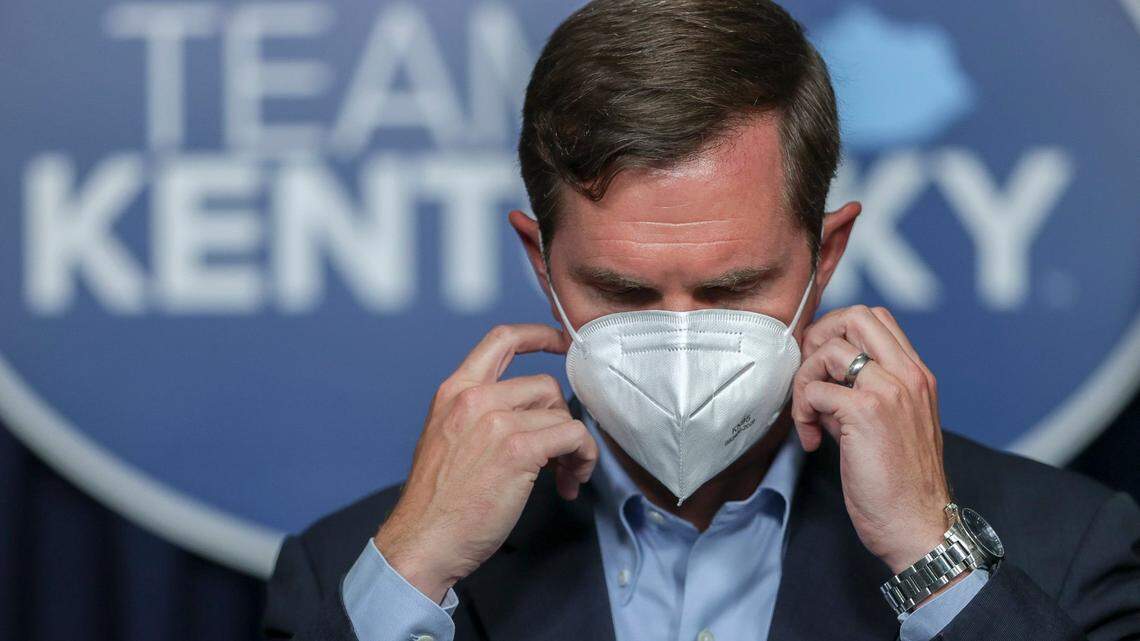 Kentucky Gov. Andy Beshear takes off his mask during a media briefing about the COVID-19 pandemic at the state Capitol in Frankfort, Ky., on Monday, Aug. 23, 2021.