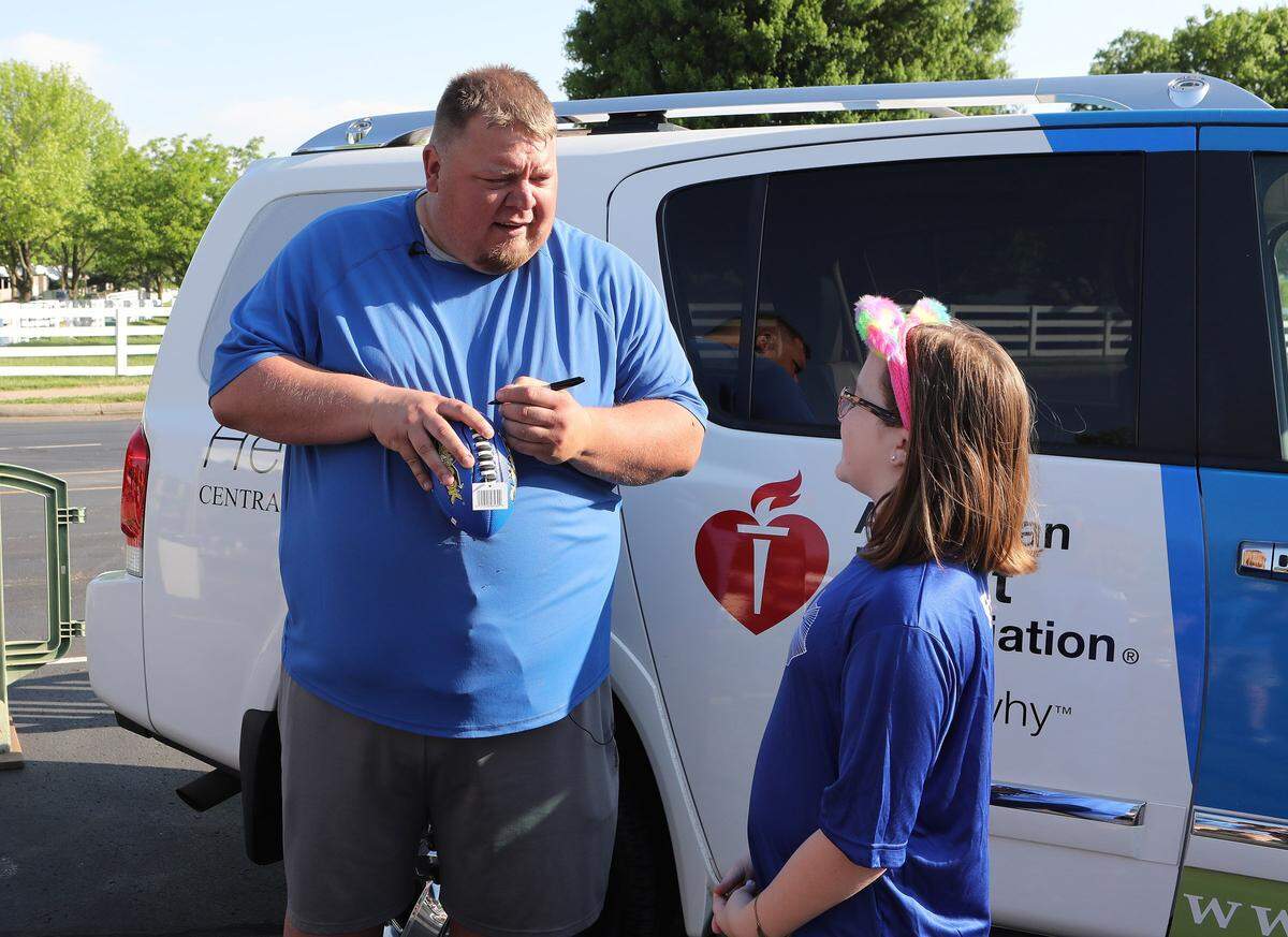 Jared Lorenzen signed a souvenir football for a young fan prior to the Central Kentucky Heart Walk at Keeneland in May 2018.