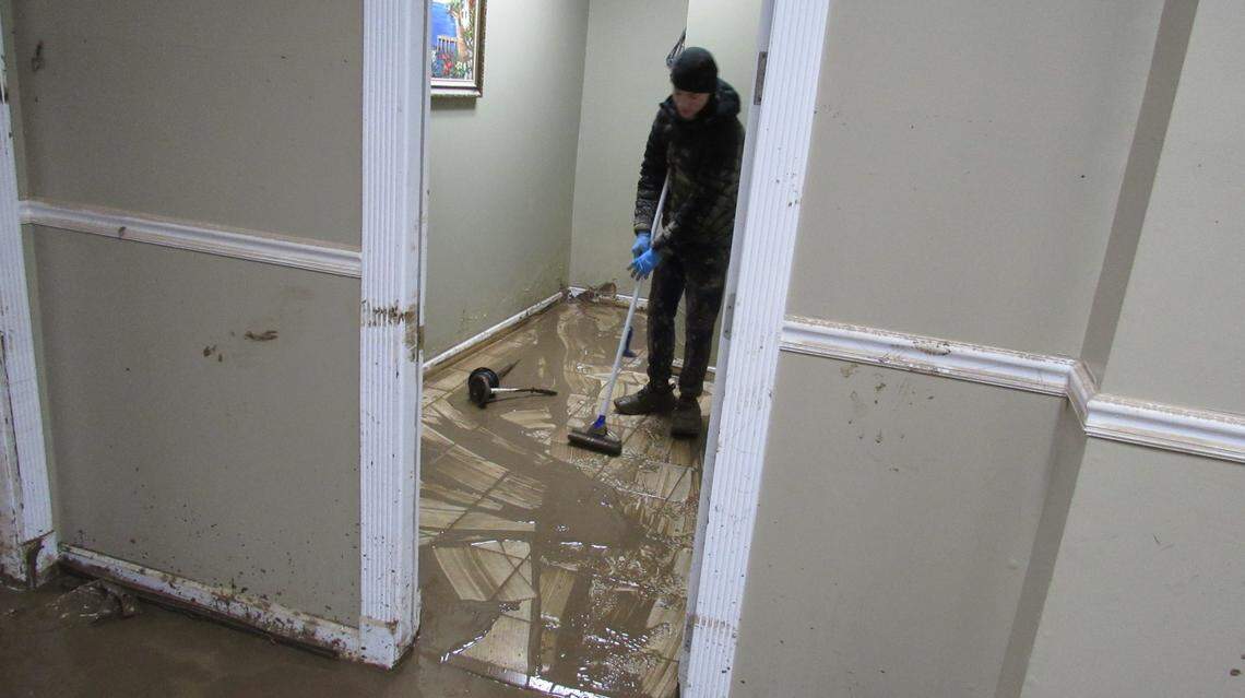 Evan Johnson, 13, pushes mud out of the law office of his father Kevin Johnson, on Feb. 17, 2025 after flooding in Hazard, Ky.
