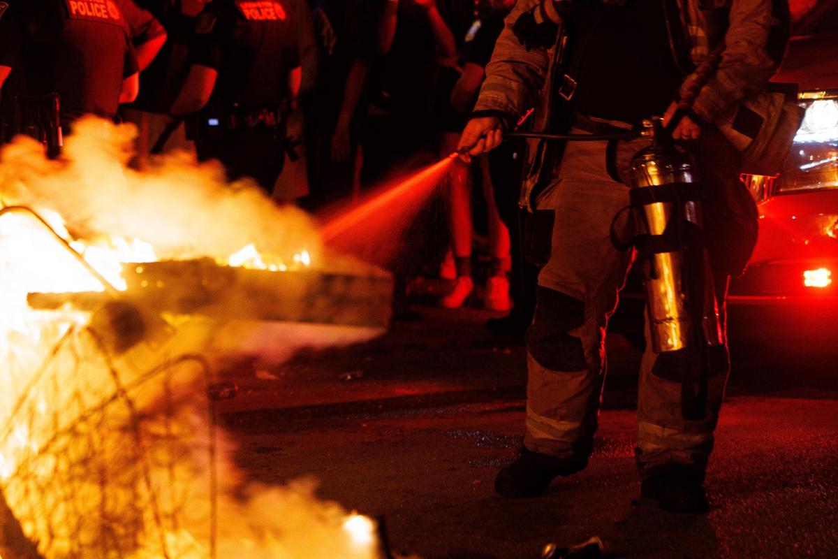 A member of the Lexington Fire Department puts out a couch fire started by University of Kentucky students and fans on State Street in Lexington, Kentucky after Kentucky football’s 26-16 win at Florida on Saturday, Sept. 10, 2022.