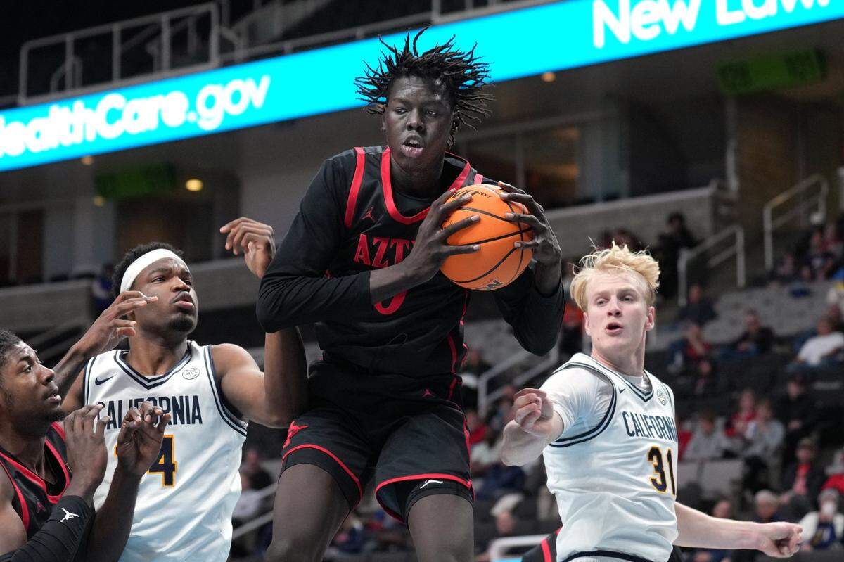 Dec 21, 2024; San Jose, California, USA; San Diego State Aztecs forward Magoon Gwath (center) rebounds against California Golden Bears forwards Lee Dort (center left) and Rytis Petraitis (31) during the second half at SAP Center. Mandatory Credit: Darren Yamashita-Imagn Images