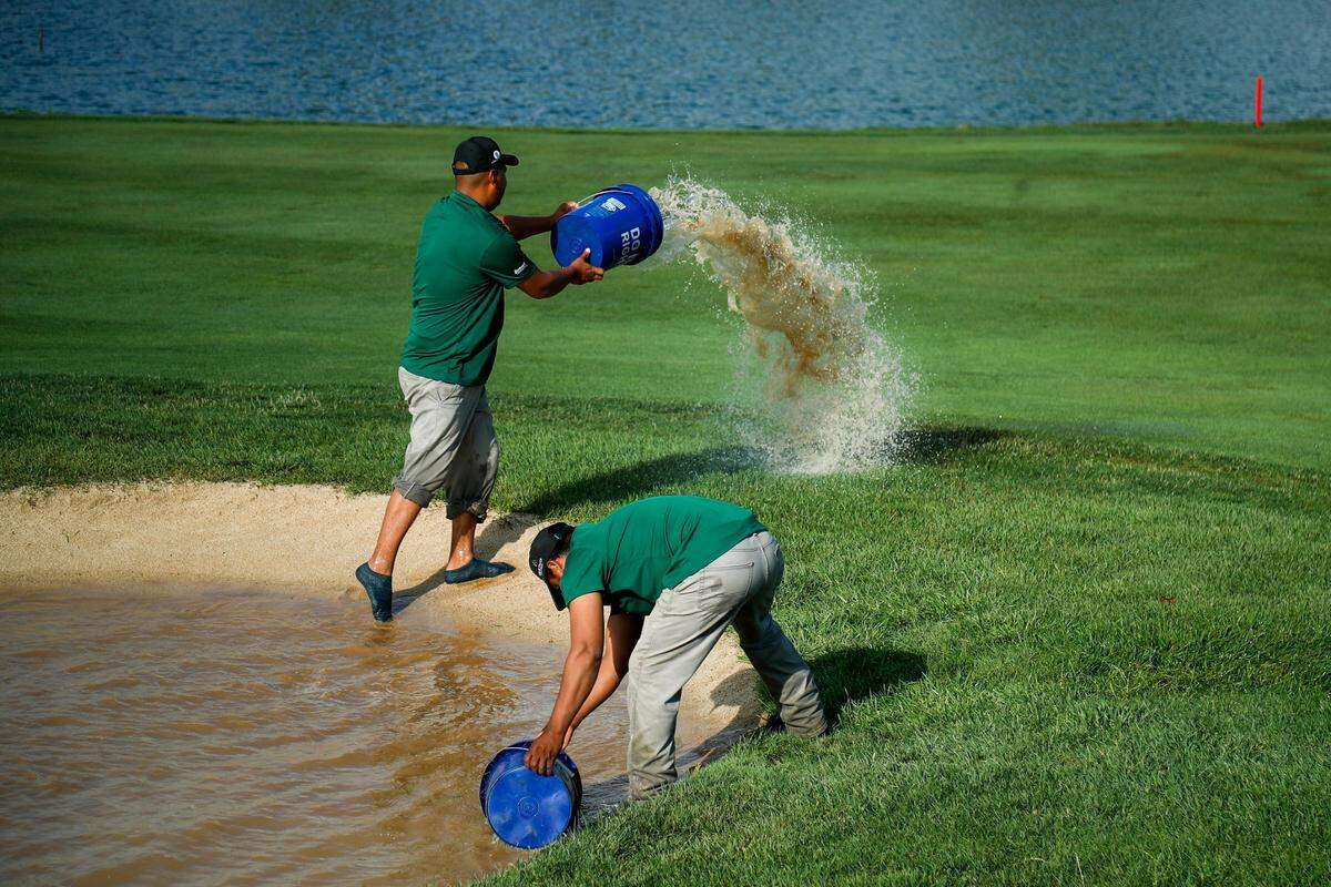 Keene Trace workers bucket water out of a bunker on the 18th hole Saturday at the Barbasol Championship at Keene Trace Golf Club in Nicholasville.