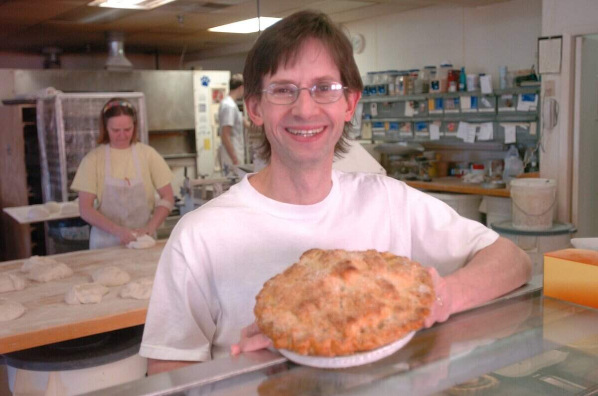 Jim Betts with an apple pie, his wife and co-owner, Francine Betts is in the  background making bread, Bluegrass Baking Company, Lexington, KY, Thursday,  March 3, 2005. Staff photo/Janet Worne